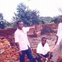 Three teachers standing in front of the building works: from left it is John, next is Boniface and on the right is Henry.